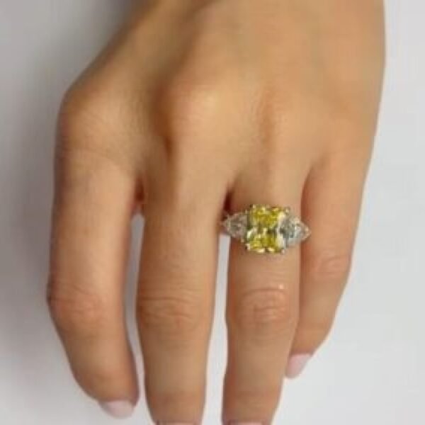 a hand wearing a fancy emerald diamond ring